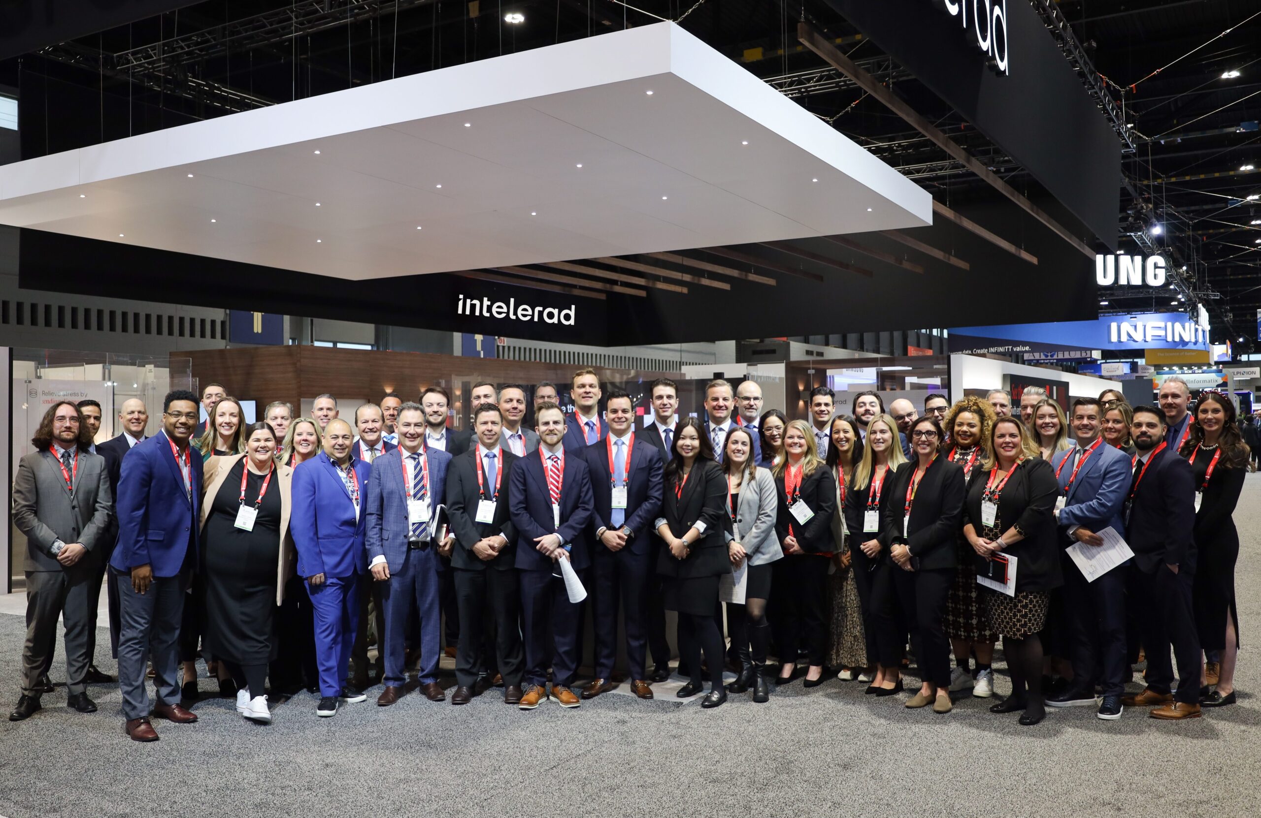 Group of professionals posing for a photo at a trade show booth with the name 