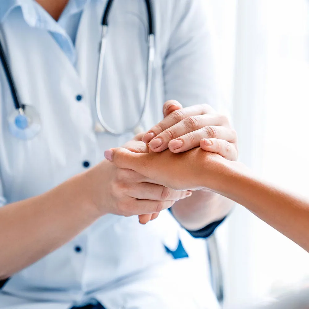 A compassionate doctor providing comfort and reassurance to a patient through a gentle hand-holding gesture.